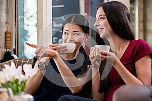 Chatty young woman pointing while sitting in a coffee shop photo