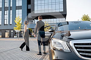 Chauffeur helps an elegant business woman gets in car