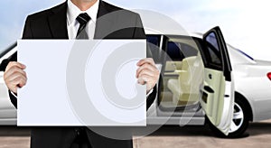 Chauffeur holding signage waiting for passenger with white limo background