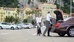 Chauffeur putting luggage in trunk, elite car service for business people