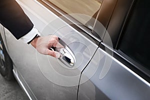 Chauffeur s hand on handle. Close-up of man in formal wear opening a passenger car door