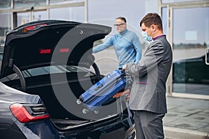 Chauffeur standing by the vehicle with the open boot