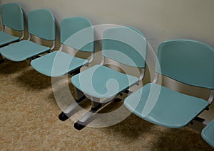 Cheap plastic chairs in a row by the wall. classic waiting room at the train station or at the doctor`s. corridor with washable su