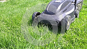 Cheap plastic electrical lawn mover on green lawn at sunny day