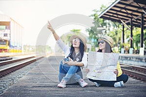 Cheap Travel and Lifestyle concept.Holiday Time,Young Traveler women wearing sneaker and sitting at train station.Asian Backpacker