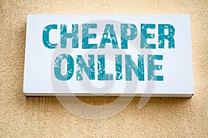 Cheaper Online. Advertising sign on the wall of a yellow building