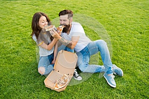 Cheat meal. Couple eating pizza relaxing on green lawn. Fast food delivery. Bearded man and girlfriend enjoy cheesy