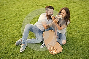 Cheat meal. Couple eating pizza relaxing on green lawn. Fast food delivery. Bearded man and girlfriend enjoy cheesy