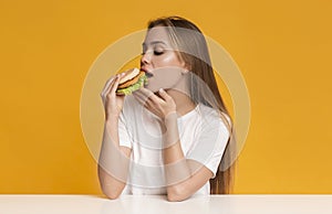 Cheat Meal. Hungry Millennial Girl Eating Tasty Burger With Appetite