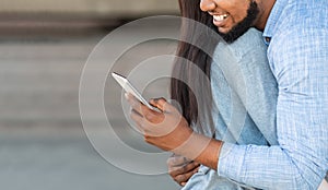 Cheating guy texting with somebody on cellphone while embracing his girlfriend