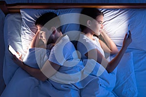 Cheating Husband And Wife Texting Lying Back-To-Back In Bedroom, Top-View