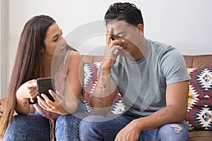 Cheating and infidelity concept - Suspicious jealous girlfriend hug boyfriend checking his phone calls contacts behind back.