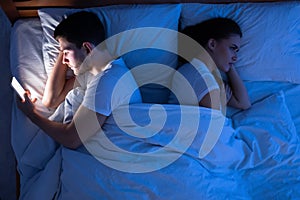 Cheating Man Texting Lying Near Girlfriend In Bed, Top-View