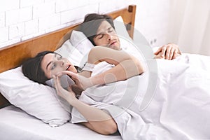 Cheating woman talking privately on cellphone in family bed