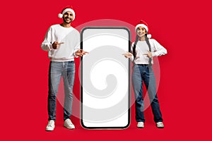 Check This. Arab Couple In Santa Hats Pointing At Big Blank Smartphone