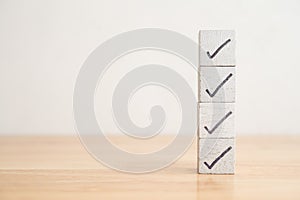 Check mark sign on white block checklist stack on wooden table background copy space. Checklist and questionnaire in business