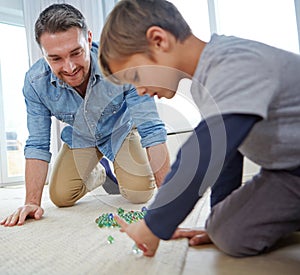 Check this move, Dad. a happy father and son playing marbles together at home.