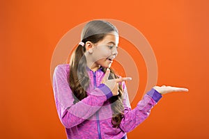 Check this out. Kid happy face show something on open palm copy space. Girl demonstrate product. Advertisement and