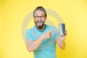 Check out new app. Guy eyeglasses cheerful pointing at smartphone. Man happy user recommends try application for