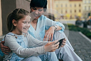 Check out this new application. little girl using tablet with her mother outdoor in city