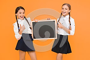 Check this out. School girls cute pupils hold blackboard copy space. Classmates initiative team yellow background. Join