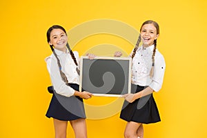 Check this out. School girls cute pupils hold blackboard copy space. School announcement concept. Classmates initiative