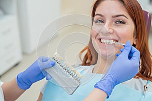 Check and select the color of the teeth in the dentist chair. Dentist makes the process of treating a beautiful young