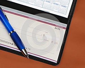 Checkbook and pen on leather background