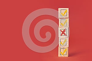 Checkbox and cross X on checklist hand drawn. wood bricks tower. construction from wooden cubes. on a red background