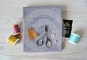 Checked fabric, leather thimble, retro scissors, wooden buttons, quilting needles and colorful threads