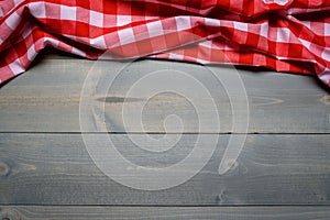 A checked gingham picnic tablecloth on old wooden table top view