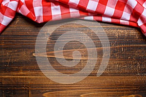 A checked gingham picnic tablecloth on old wooden table top view