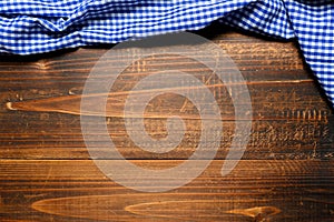 A checked gingham picnic tablecloth on old wooden table top view