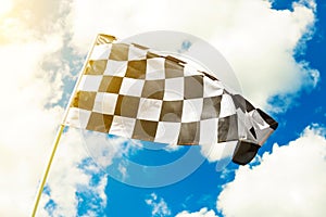 Checkered flag waving in the wind with sun flare seen