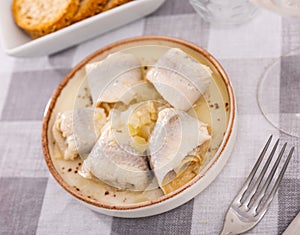 on checkered tablecloth plate with appetizer - rolls of salted Atlantic herring fillet with onions