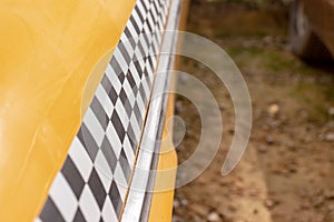 Checkered taxi sign on a yellow taxi car doors close up, copy space