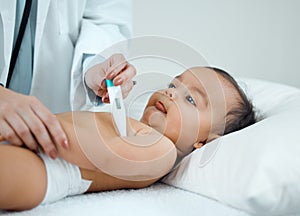 Checking for any symptoms of fever. a paediatrician taking a babys temperature with a thermometer in a clinic.