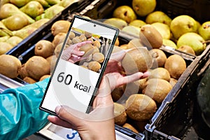 Checking calories on a kiwi fruit in store with smartphone