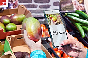 Checking calories on a mango fruit in store with smartphone