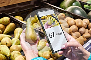 Checking calories on pear fruit in store with smartphone