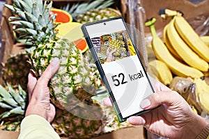 Checking calories on pineapple in store with smartphone