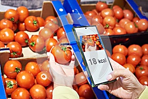 Checking calories on tomato vegetable in store with smartphone