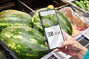 Checking calories on watermelon in store with smartphone