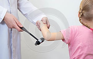 Checking the child`s elbow reflex with a neurological hammer, close-up. Nervous system