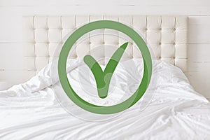 Checking for cleanliness. Horizontal shot of white comfortable bed and green approval sign detecting good sanitation conditions th