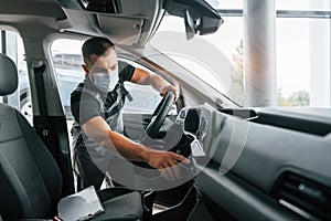 Checking control panel. Man in uniform is working in the autosalon at daytime