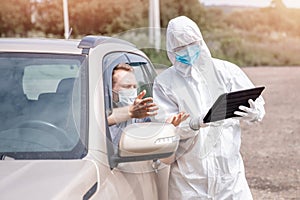 Checking and disinfecting car for virus COVID-19 and bubonic plague border of city and country. Doctor in biohazard suit