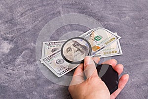 Checking dollar bill for authenticity with magnifying glass