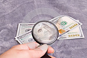 Checking dollar bill for authenticity with magnifying glass