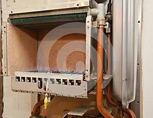 Checking furnace blue gas flame inside an open natural gas boiler during heating maintenance